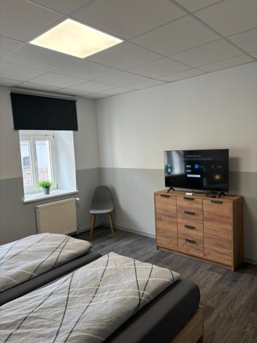 a bedroom with a bed and a television on a dresser at Ferienwohnung H&M Immobilien Querfurt 2 in Querfurt