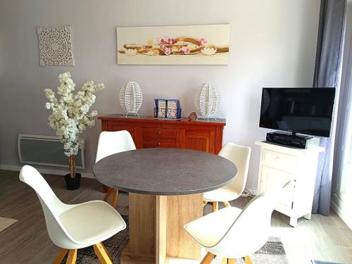 une salle à manger avec une table et des chaises blanches dans l'établissement Appartement rénové avec terrasse VUE SUR MER à TREGASTEL - Ref 481, à Trégastel