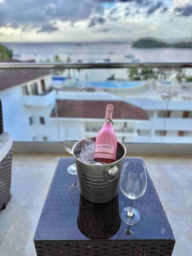 a bottle of wine in a bucket on a table with a glass at Stunning Bay View Condo, Pool in Santa Bárbara de Samaná