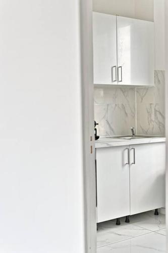 - une cuisine blanche avec un évier et des placards blancs dans l'établissement Appartement Rose Moderne Proche de la capitale III, à Gagny