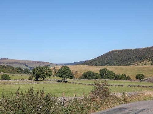 a field of grass with trees and a road at Knoll View in Bradwell