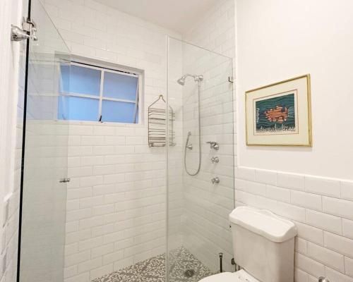 a white bathroom with a shower and a toilet at Deco House with Park View Rooftop in Mexico City