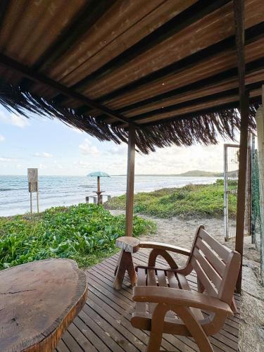 a wooden deck with a bench and an umbrella on the beach at Casa de praia em Japaratinga.(Pé na areia!) in Japaratinga