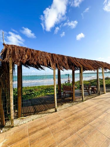 a pavilion with a straw roof on the beach at Casa de praia em Japaratinga.(Pé na areia!) in Japaratinga