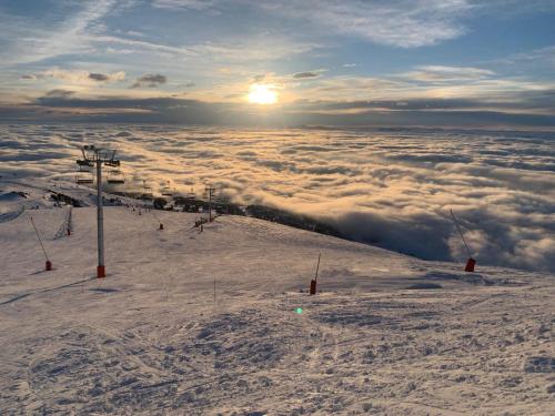 a ski lift on top of a mountain above the clouds at Les Flocons in Chamrousse