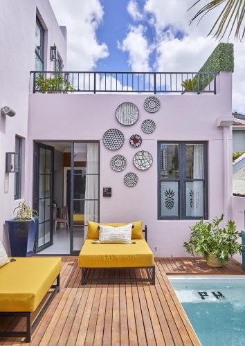 a house with a yellow couch on a deck next to a pool at Pineapple House Boutique Hotel in Cape Town