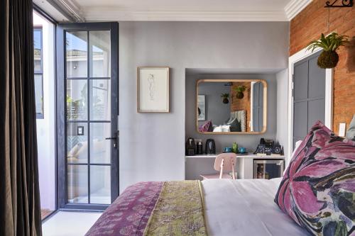 a bedroom with a bed and a mirror and a desk at Pineapple House Boutique Hotel in Cape Town