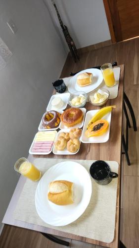 a table with plates of breakfast foods and orange juice at Chalés Recanto na Serra in Gonçalves