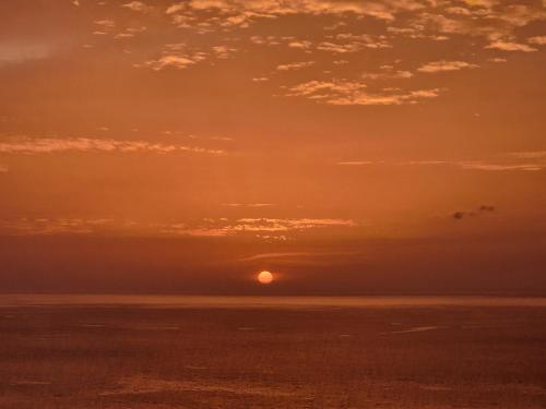a sunset over the ocean with the sun in the sky at Casa Saúde in Seladinha