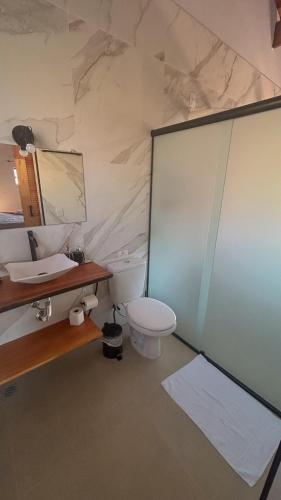 a bathroom with a toilet and a sink and a mirror at Chalés Recanto na Serra in Gonçalves