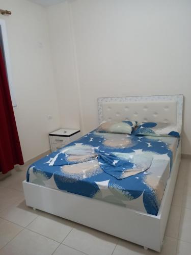 a bed with a blue and white comforter and pillows at Adria Apartment in Lalzit Bay