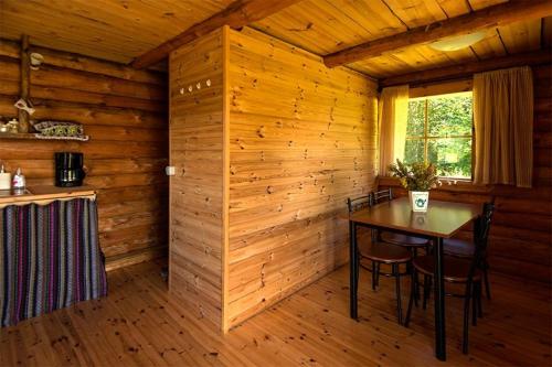 a dining room with a table in a log cabin at Veskikivi Holiday Home in Mäebe