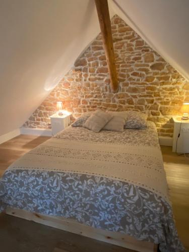 una cama en una habitación con una pared de ladrillo en Au charme de la Cour, en Auxonne