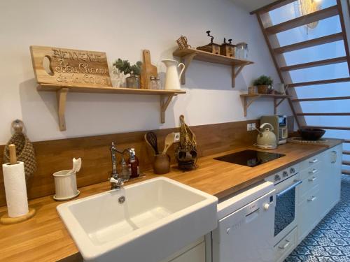 Una cocina con fregadero y encimera de madera. en Au charme de la Cour, en Auxonne