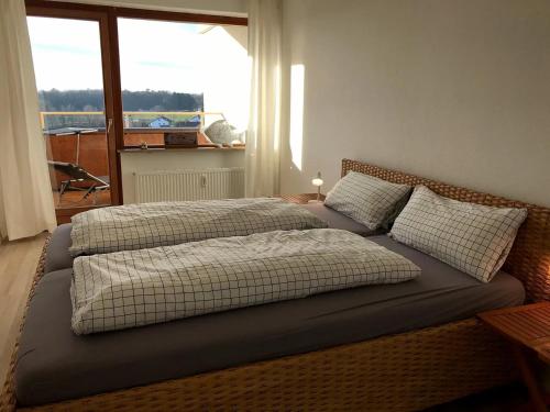 Dos camas en un dormitorio con ventana. en Ferienwohnung Alina- Penthouse Wohnung mit atemberaubendem Blick zum Bodensee, en Kressbronn am Bodensee