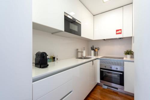 a white kitchen with white cabinets and a stove at Porto Premium River View II in Porto