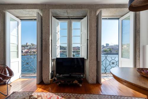 a living room with large windows and a tv at Porto Premium River View II in Porto