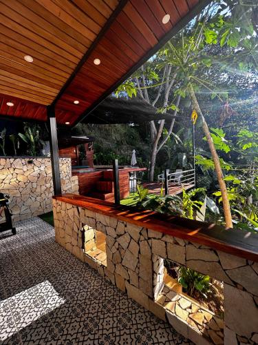 an outdoor patio with a stone wall and a wooden roof at Cabaña Cedro Amarillo - moderna con jacuzzi en Sopetran, cerca de Medellín in Sopetran