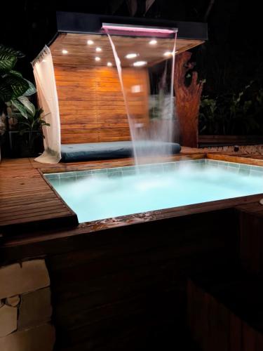 a swimming pool with a water fountain on a deck at Cabaña Cedro Amarillo - moderna con jacuzzi en Sopetran, cerca de Medellín in Sopetran