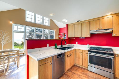 a kitchen with wooden cabinets and a red wall at Waterfront Bellingham Bliss Steps to Beach! in Bellingham