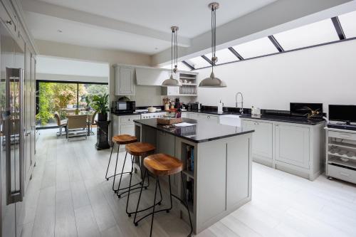 a kitchen with white cabinets and a island with stools at Beautiful Oxford Town House in Oxford