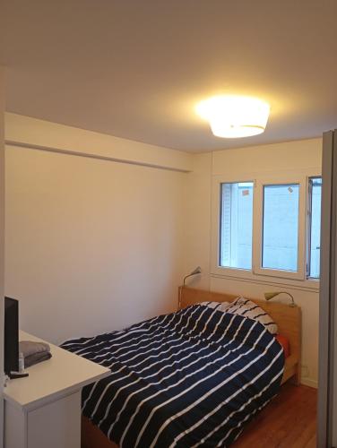 une chambre avec un lit et deux fenêtres dans l'établissement La Citadelle, à Arcueil