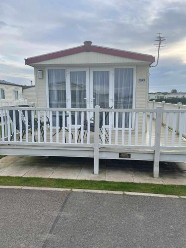 a house with a white porch and a white fence at PG101 6 BERTH DELUXE ON THE GOLDEN PALM CHAPEL st LEONARD PG101 in Chapel Saint Leonards