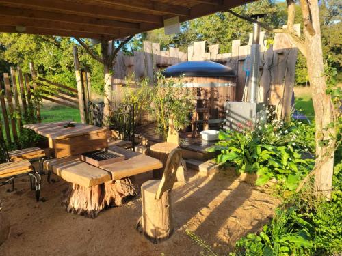 a patio with wooden tables and benches in a yard at La terre du milieu 87 in Saint-Sulpice-les-Feuilles