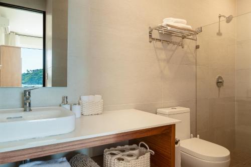 Playa Sur Paradise - Beachfront Living في سانتا كروز هواتولكو: حمام مع حوض ومرحاض ومرآة