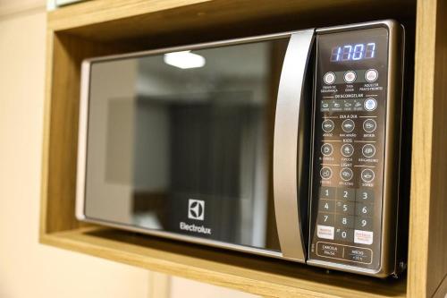 a microwave oven sitting on a wooden shelf at FLATS - DUO JK in Sao Jose do Rio Preto