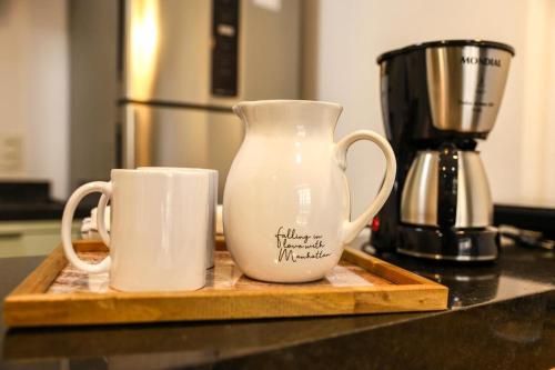 two coffee mugs sitting on a wooden cutting board at FLATS - DUO JK in Sao Jose do Rio Preto