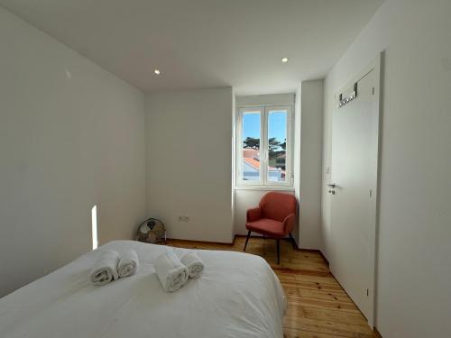 - une chambre blanche avec un lit et une chaise rouge dans l'établissement Estoril Escape - Family & Friends Beach Getaway, à Estoril