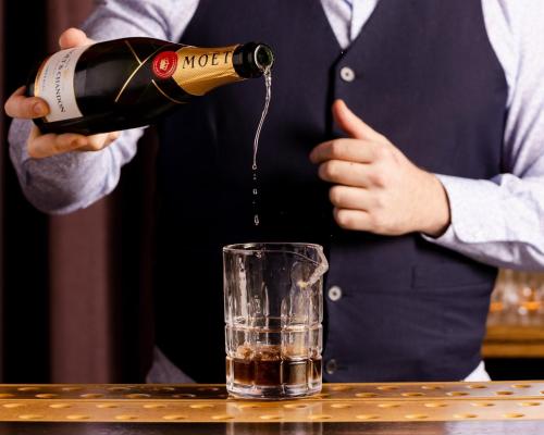 a man pouring a bottle of wine into a glass at Kimpton Fitzroy London by IHG in London