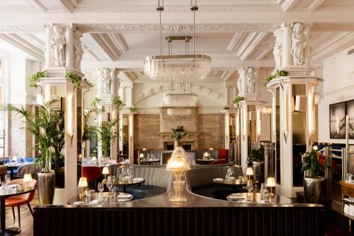 a restaurant with a chandelier and tables and chairs at Kimpton Fitzroy London by IHG in London