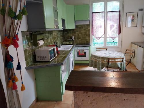 une cuisine avec des armoires vertes et une table à l'intérieur dans l'établissement Halte-jardin du hâvre, à Précy-sur-Oise