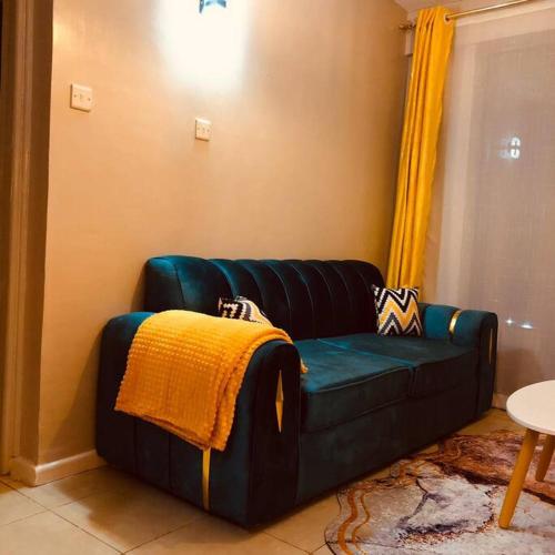 a green couch in a living room with a yellow blanket at Your Luxurious Escape on Kiambu Rd ,Comfort, Convenience, and Connectivity Await in Kiambu