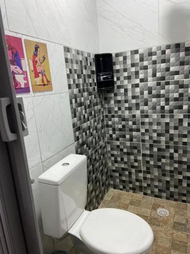 a bathroom with a toilet and a tiled wall at Kitnet Europa in Bonito