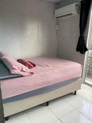 a small bed with a pink sheet on it at Kitnet Europa in Bonito