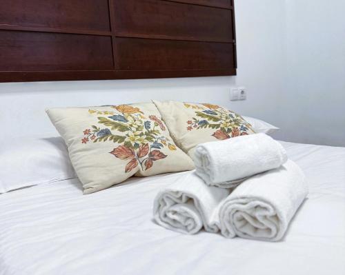 1 cama blanca con 2 almohadas y toallas en Apartamento acogedor en Triana - wifi, en Sevilla