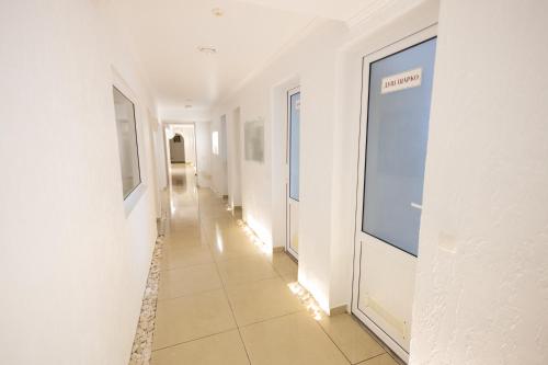 a hallway with white walls and a tile floor at Fantasia Hotel in Polyana