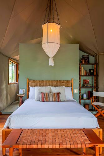 a bedroom with a large bed with a chandelier at Sleeping Giant Rainforest Lodge in Belmopan