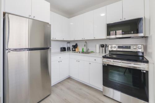 a kitchen with white cabinets and a stainless steel refrigerator at Prime Location Apt on Calle Ocho in Little Havana in Miami