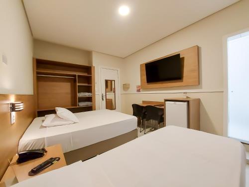a hotel room with two beds and a desk and a television at Hotel Itamarati Centro-República in Sao Paulo