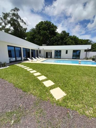 a building with a swimming pool and a grass yard at Espectacular Casa Quinta en Riachuelo Cts in Laguna Brava