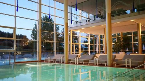 バート・ヴァルタースドルフにあるWHIRLPOOL-SUITE AMADEUS - Weitblick - Golf & Wellness - direkter Bademantelgang - ADULTS ONLYの大きな建物で、椅子と窓付きのプールがあります。