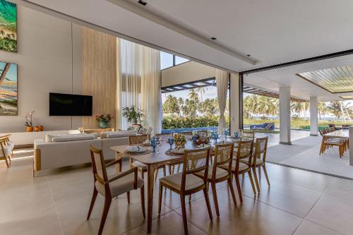 a dining room and living room with a table and chairs at Nossa Casa | Frente Mar, 5 Suítes Exclusivas in Praia do Forte