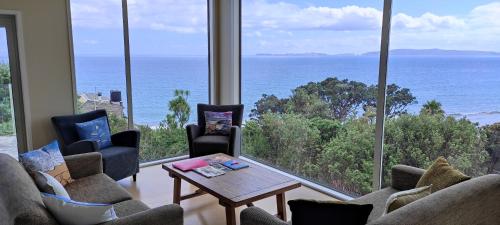 a living room with a view of the ocean at The Wow House in Kuaotunu