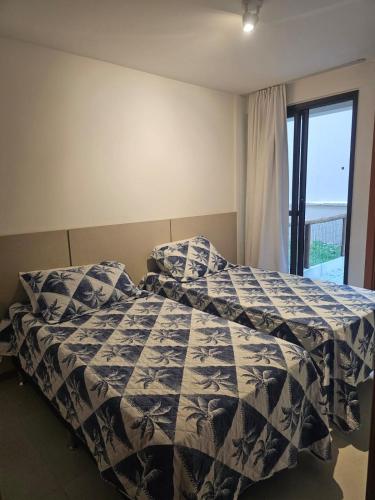 a bedroom with a bed with a blue and white comforter at Village Térreo Acqua Guarajuba in Guarajuba