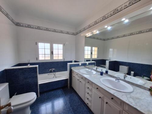 a bathroom with two sinks and a tub and a toilet at Villa cerca de Valencia con piscina junto a la montaña in Vilamarxant