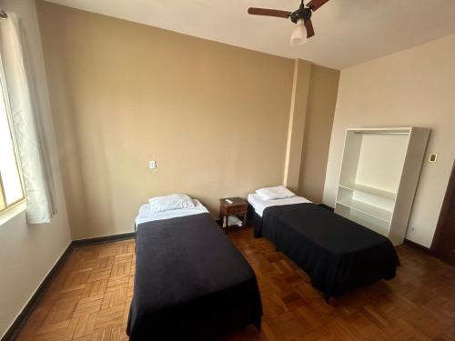 a room with two beds and a ceiling fan at Hotel Jaú by Easy Hotéis in Jaú